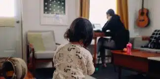 girl in white and black shirt holding baby in white onesie